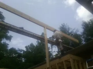 Carpenter setting a ridge beam over a new addition frame — Ice Dam Removal by Roofing Brothers in Caruthers