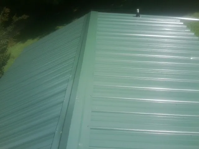 New green metal panels meeting at the ridge of a roof — Flat Roof Repair work by our crew in Caruthers