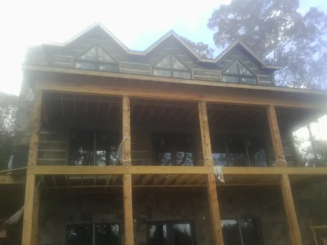 Dormers and porch framing on a large log home under construction — Roof Coating work by our crew in Caruthers